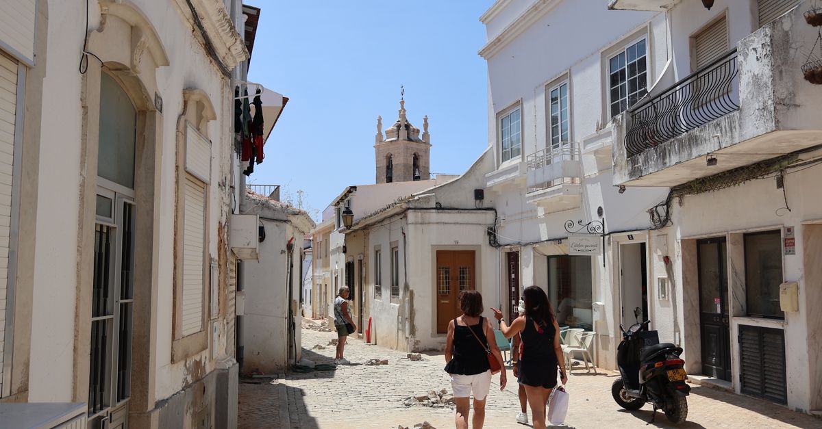 Whitewashed houses with tiled roofs above an Algarve bay, the sea beyond