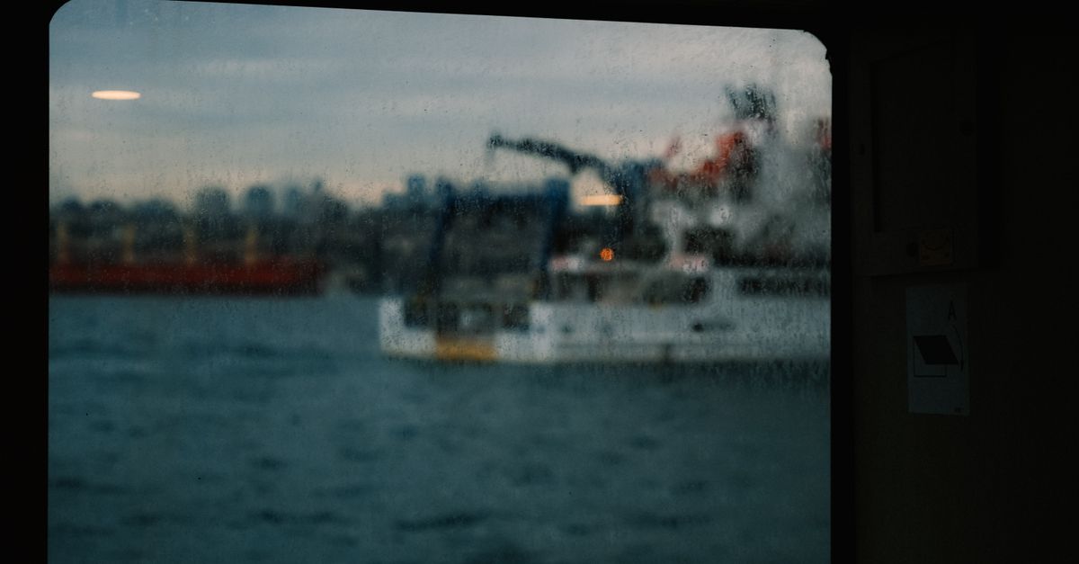 Raindrops on a window pane, with the whitewashed houses of an old-town alley blurred behind it