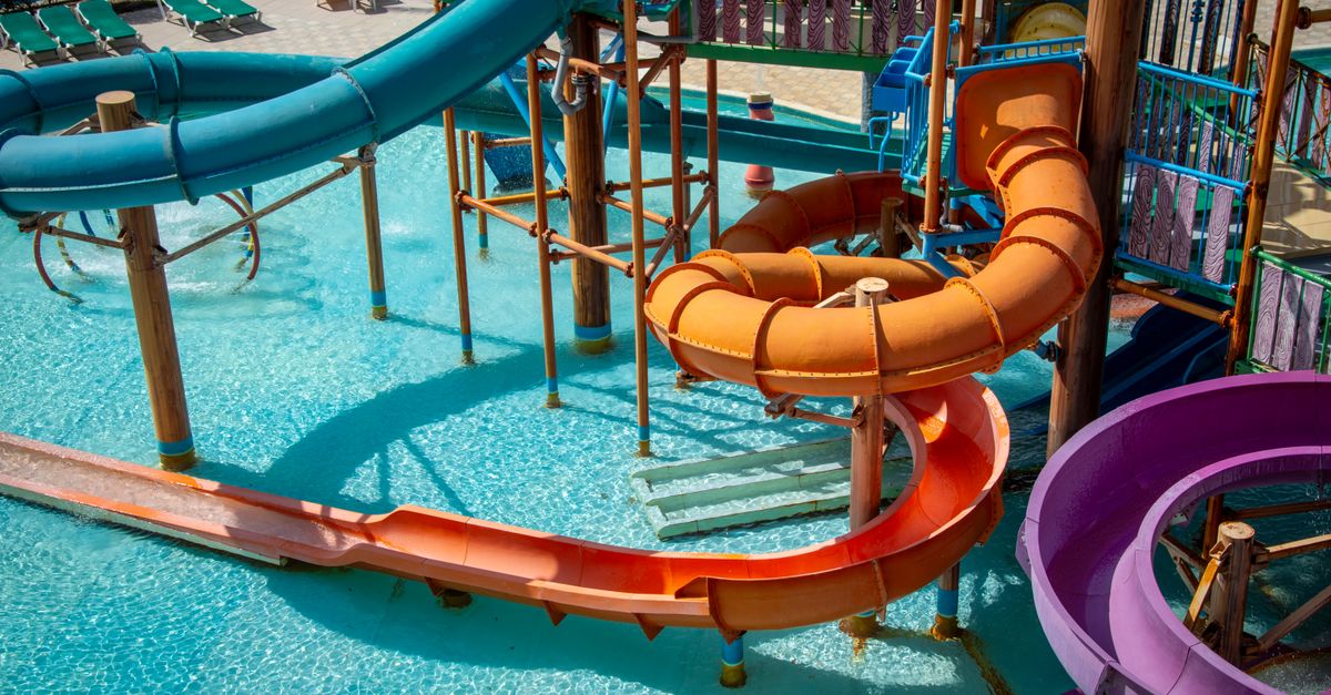 Colourful water slides at a water park, with a pool full of swimmers below